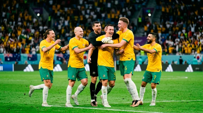 Australian Socceroos players in gold jerseys celebrating on pitch during international football match